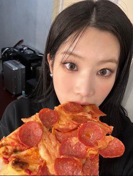 a woman eating a slice of pizza with pepperoni on it's crust and looking at the camera