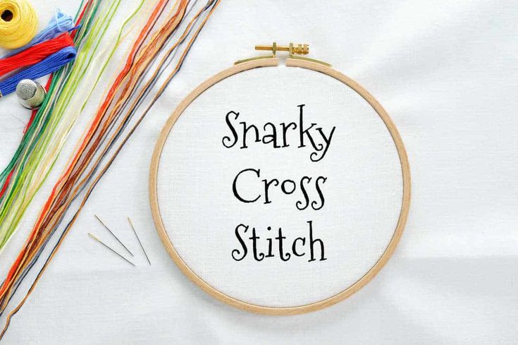 a close up of a cross stitch on a table with scissors and other crafting supplies