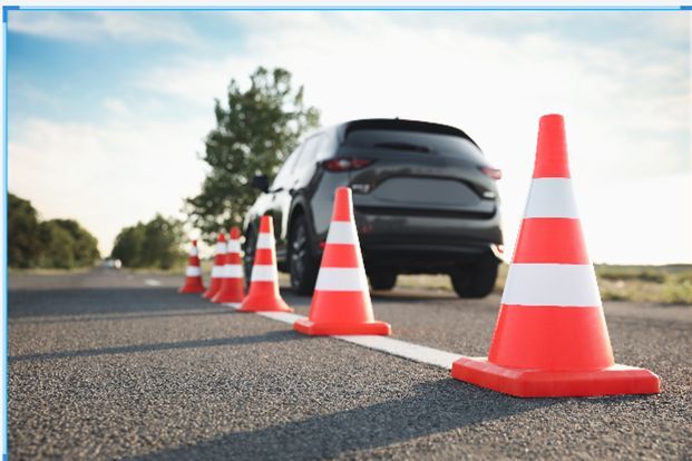 a car driving down the road with orange traffic cones around it and a black car in the background