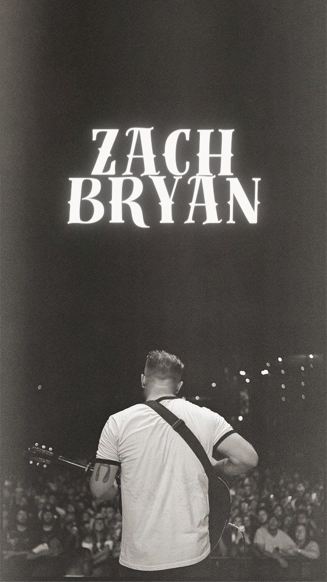 a black and white photo of a man holding a guitar in front of a crowd