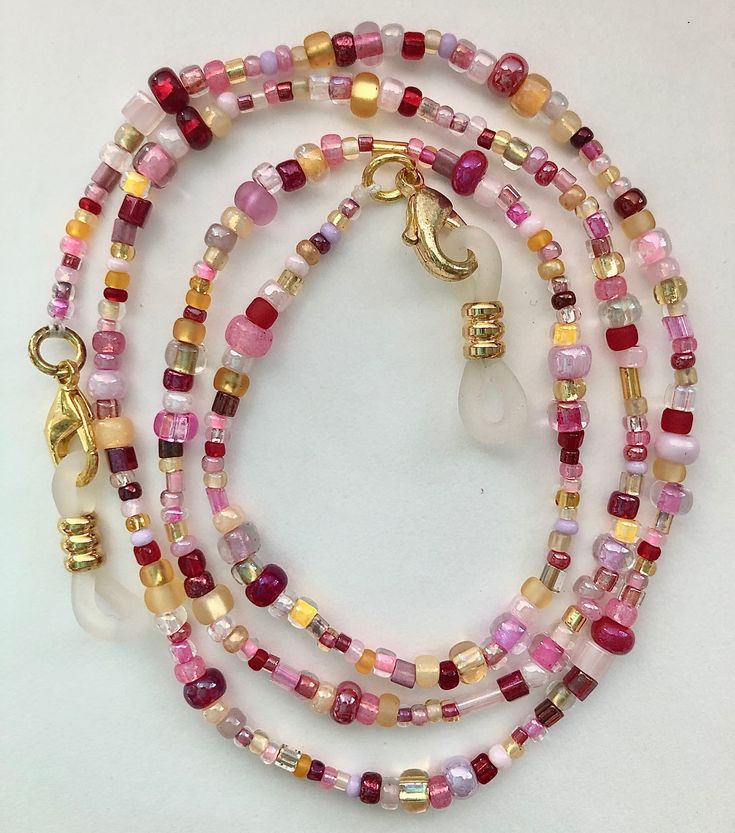 Multiple shades of purple, pink and red with gold and yellow make up this beaded eyeglass chain. Clear rubber and gold eyeglass holders are attached at both ends. Approximately 26 or 31 inches long in total length with the beaded portion being about 23 or 29 inches long. If you would prefer black rubber connectors instead of clear just let me know in the comment section! Also if you are wanting to use this chain for a mask let me know and I will remove the rubber connectors and swap out the lobs Pink Glass Beaded Chain Jewelry, Pink Glass Jewelry With Beaded Chain, Gold Adjustable Single Strand Glasses Chain, Gold Single Strand Adjustable Glasses Chain, Handmade Adjustable Pink Glasses Chains, Red Beaded Glasses Chains For Gift, Red Beaded Glasses Chains As Gift, Adjustable Pink Glasses Chains As Gift, Gold Glasses Chains With Lobster Clasp And Round Beads