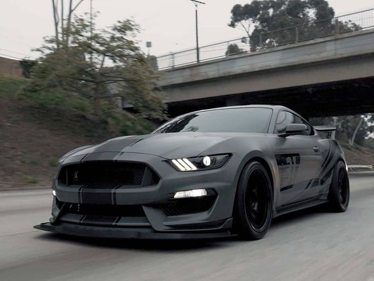 the grey mustang is driving down the road