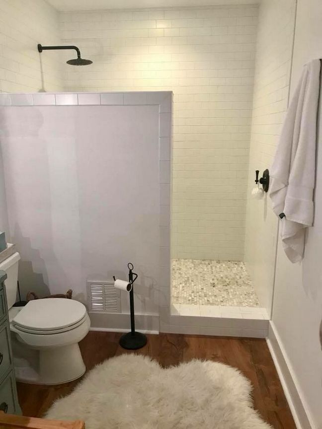 a bathroom with a toilet, shower and rug on the floor