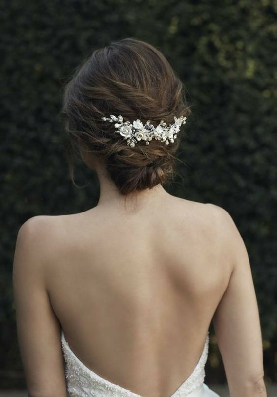 the back of a woman wearing a wedding dress with flowers on it's head