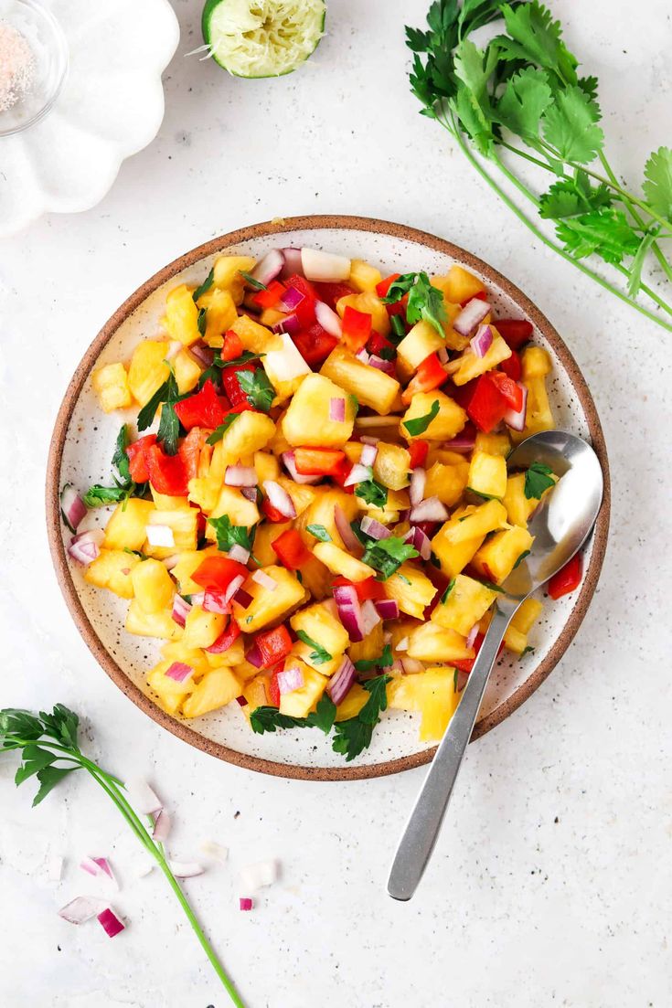 a bowl filled with pineapple, red onion and cilantro salad on top of a white table