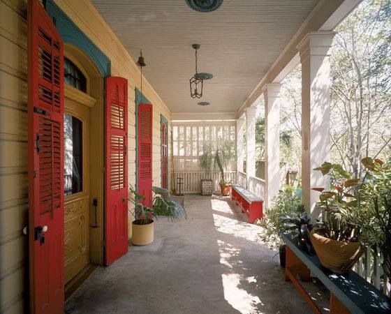 the front porch has red shutters and potted plants on either side of it