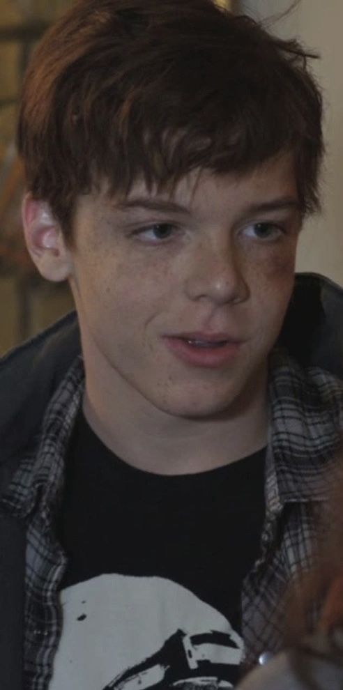 a young boy is looking at something in the distance while wearing a black and white shirt