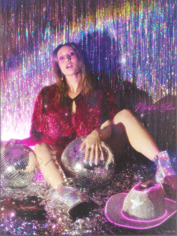 a woman sitting on the ground in front of disco balls