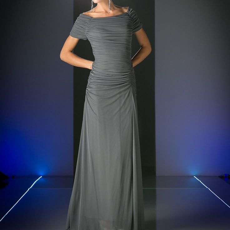 a woman in a gray dress standing on a runway with her hands on her hips