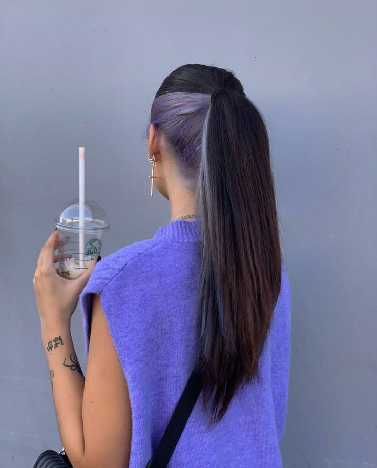 a woman is holding a water bottle and looking at her cell phone while standing against a wall