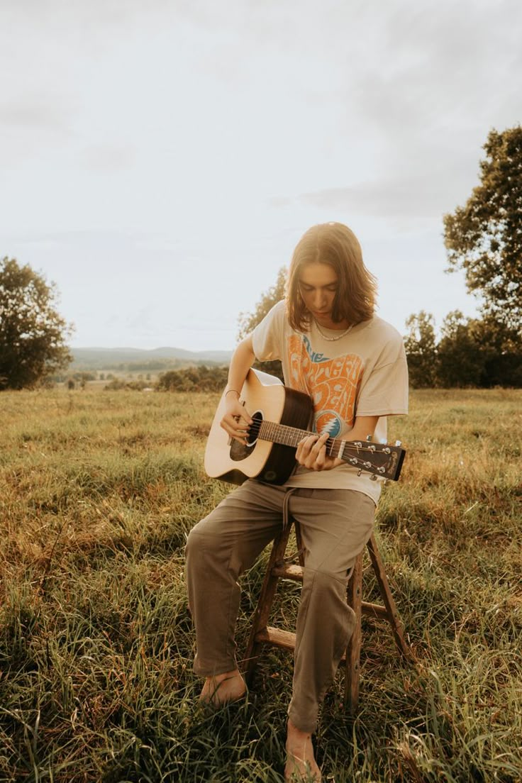 a man sitting in a chair playing an acoustic guitar