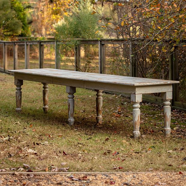 an old wooden bench sitting in the middle of a field with leaves on the ground