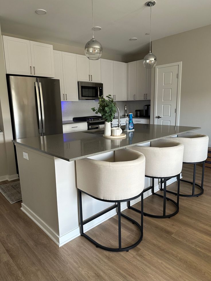 a kitchen with an island and four stools in front of the counter top area