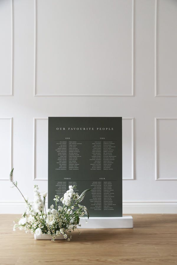 a bouquet of flowers sitting on top of a wooden table next to a black sign