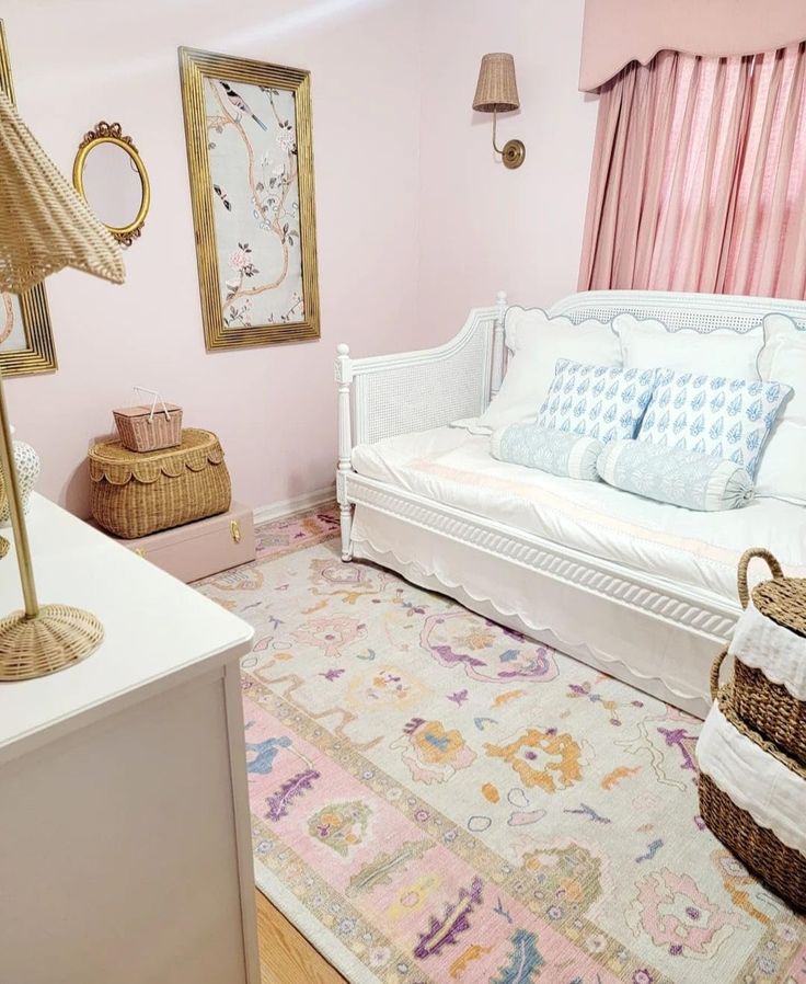 a white day bed sitting in a bedroom next to a dresser and window with pink curtains