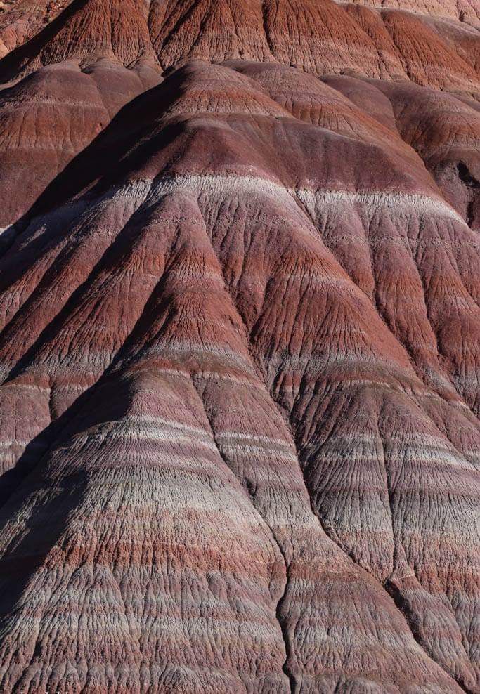 the mountains are colorfully colored and have ridges in it's sides, as seen from an airplane