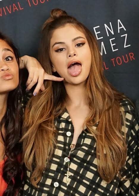 two women making funny faces while standing next to each other in front of a sign