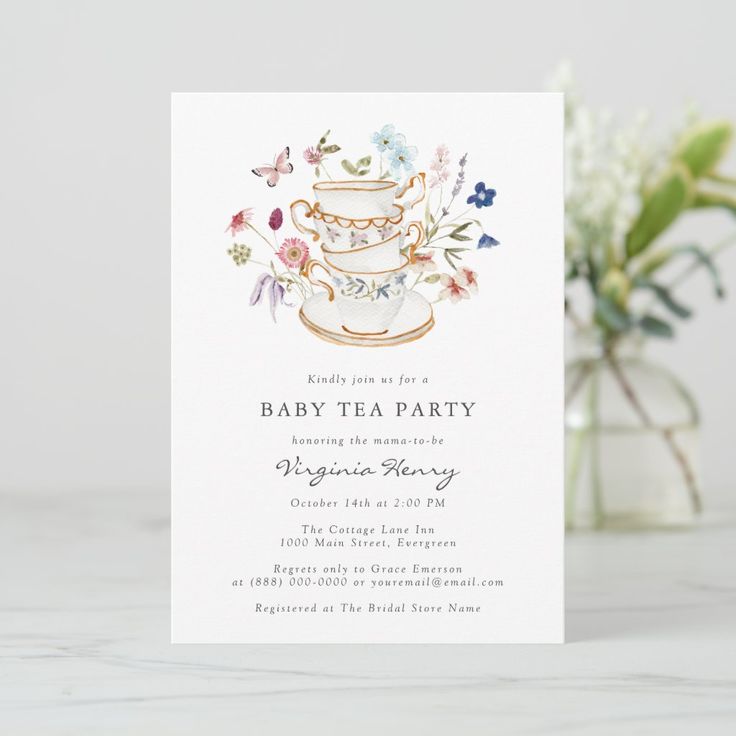 a baby tea party is set up on a table next to a vase with flowers