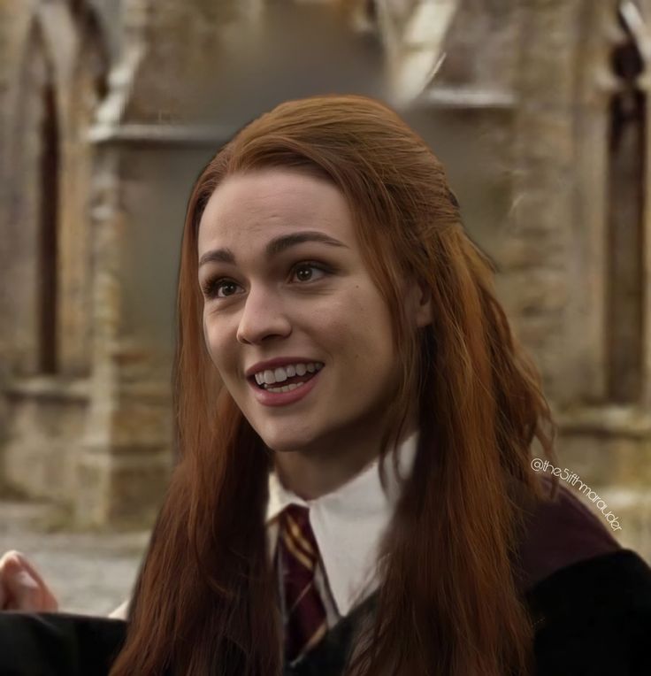 a woman with long red hair wearing a harry potter outfit and smiling at the camera