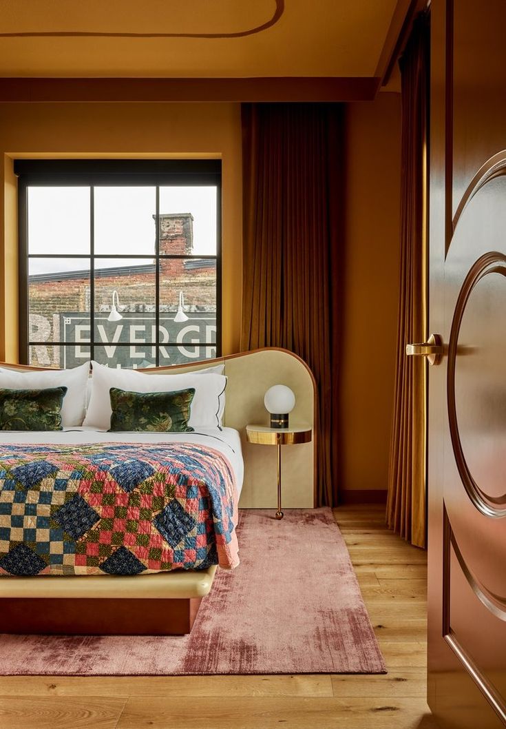 a bedroom with a large bed in front of a window and rug on the floor