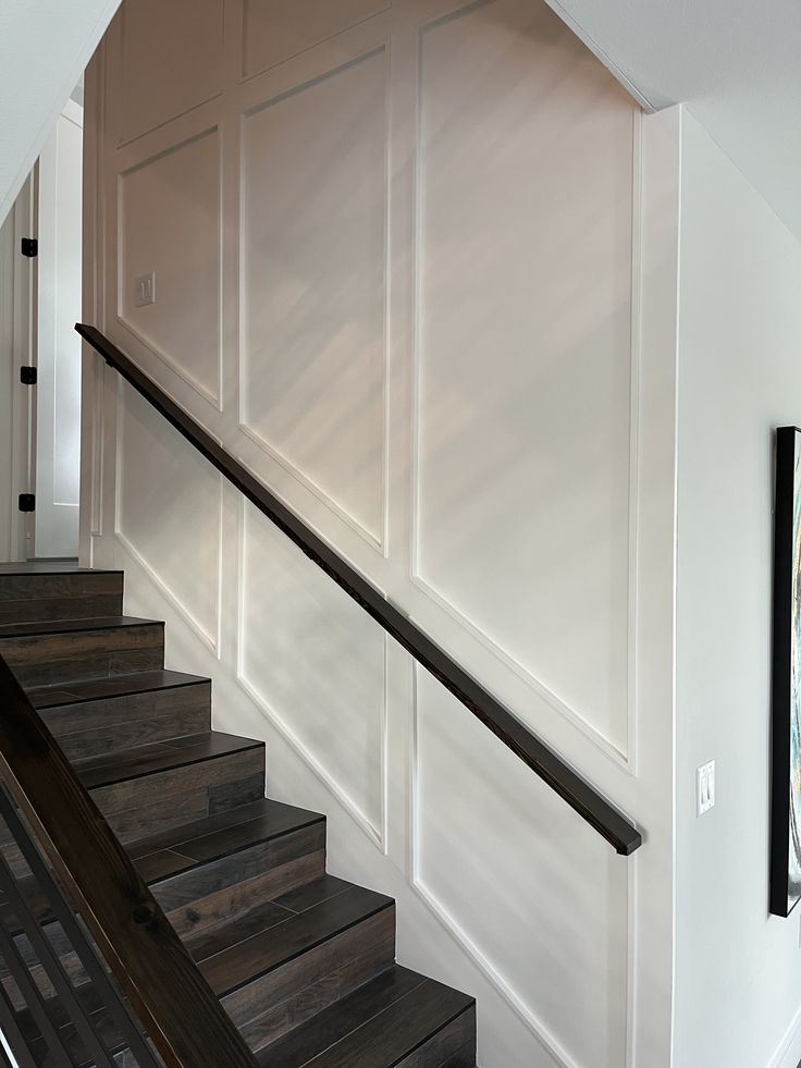 there is a staircase leading up to the second floor with white walls and dark wood handrails