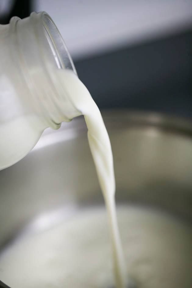 milk being poured into a pot on the stove