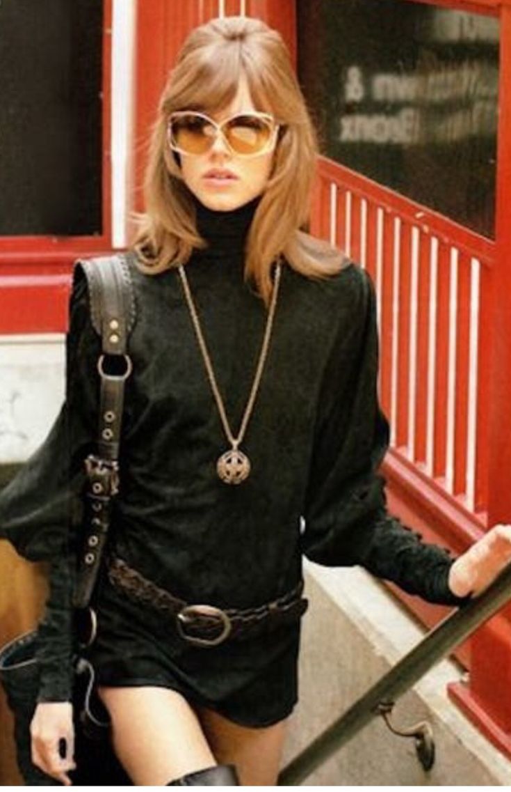 a woman in black dress and knee high boots standing on stairs with her handbag