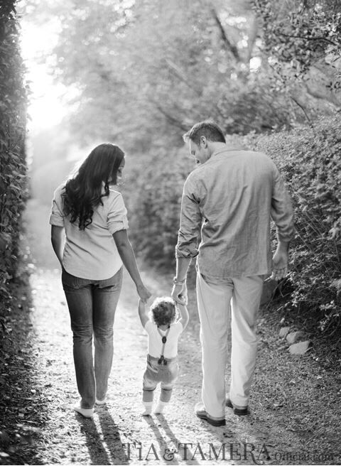 a man and woman holding hands while walking down a path with a small child in their hand