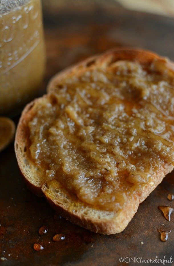 two pieces of bread sitting on top of a wooden cutting board next to a jar of peanut butter