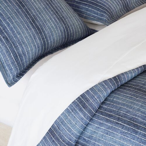 a bed with blue and white striped comforter next to pillows on top of it