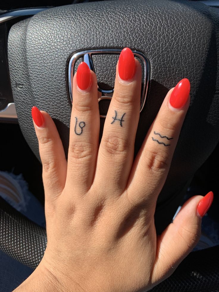 a woman's hand on the steering wheel of a car with red nail polish