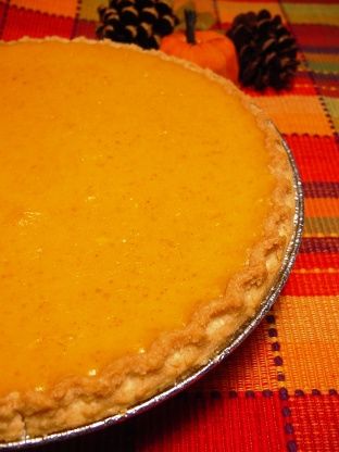 a pie sitting on top of a table next to pine cones and pumpkins in the background