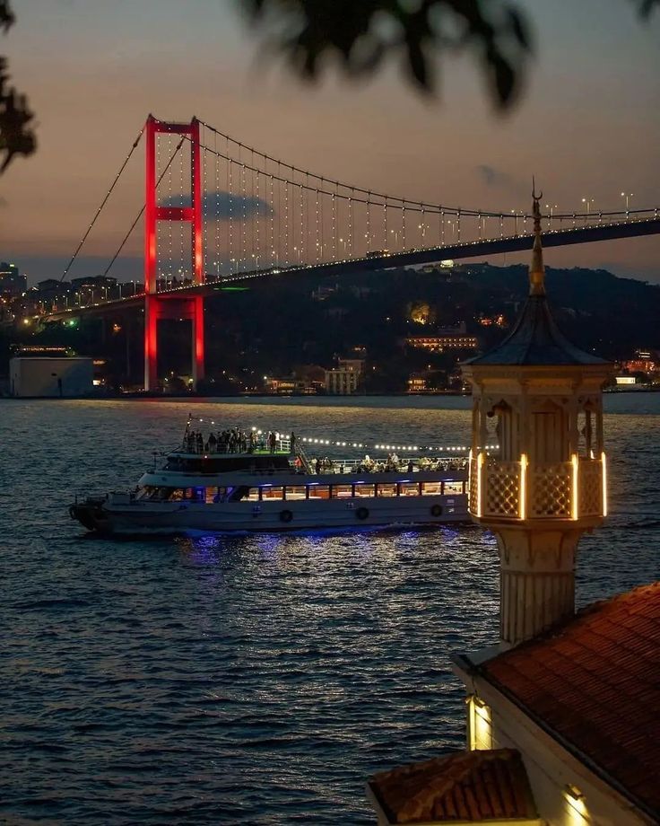 a boat is in the water near a large bridge at night with lights on it