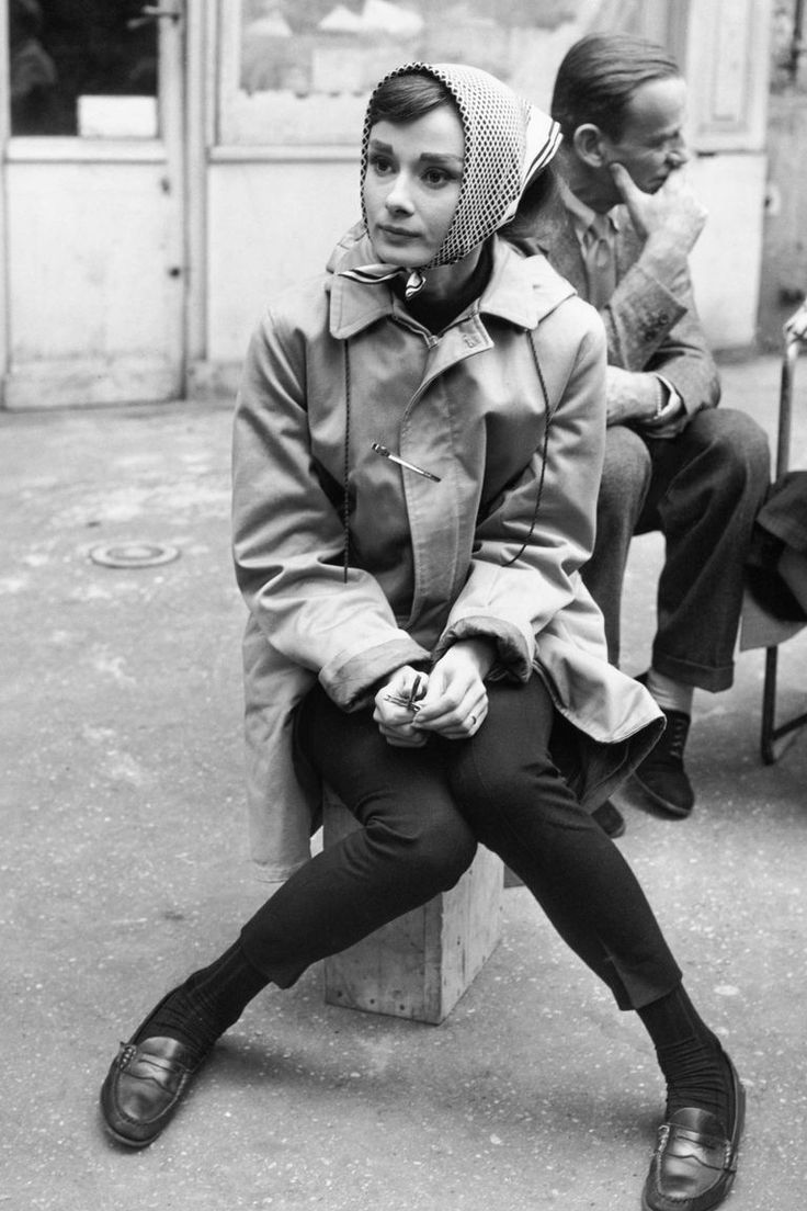 black and white photograph of woman sitting on bench in front of building with two men