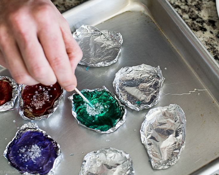 a person is dipping something into tin foil on a baking pan with other food items