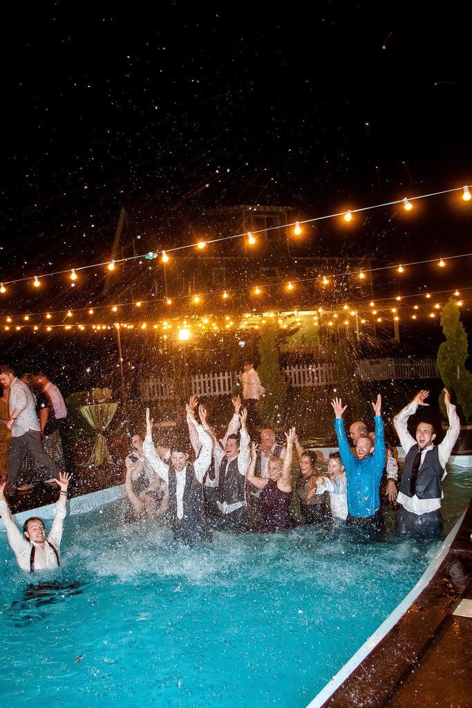 a group of people standing in a pool with their arms up and hands raised above the water