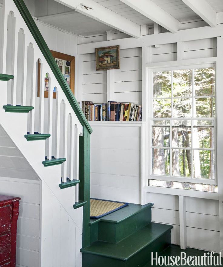 there is a green stair case next to the bookshelf in this room with white walls