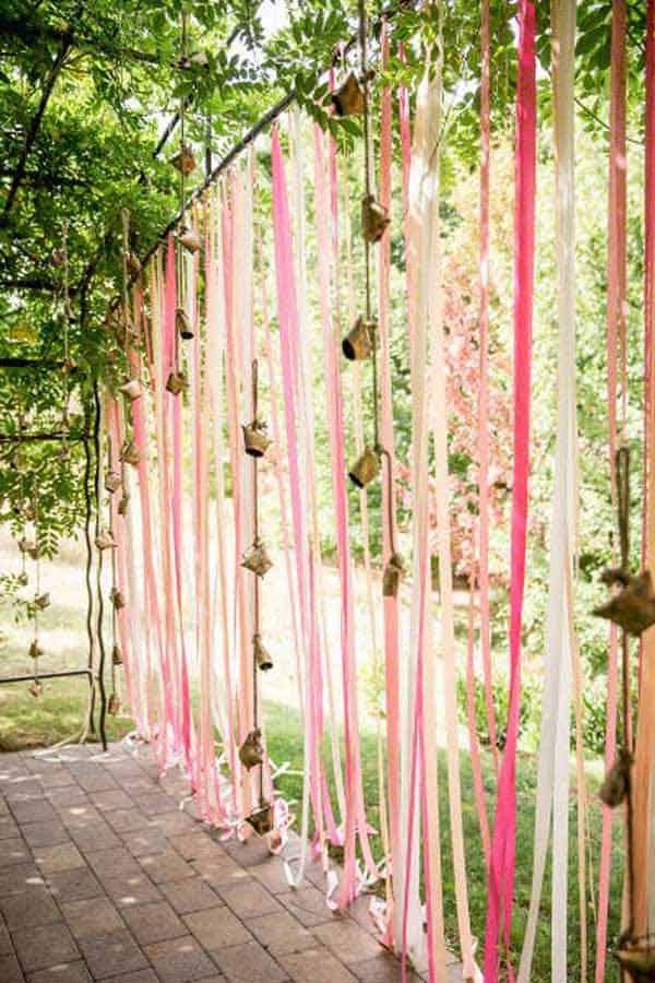 an outdoor ceremony with pink and white streamers hanging from the side of the aisle