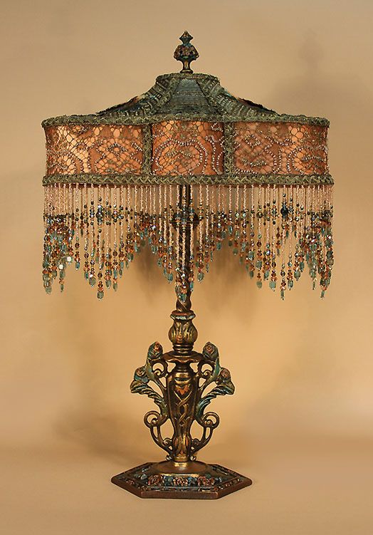 an ornate lamp with beaded shades on the shade is shown in front of a beige background