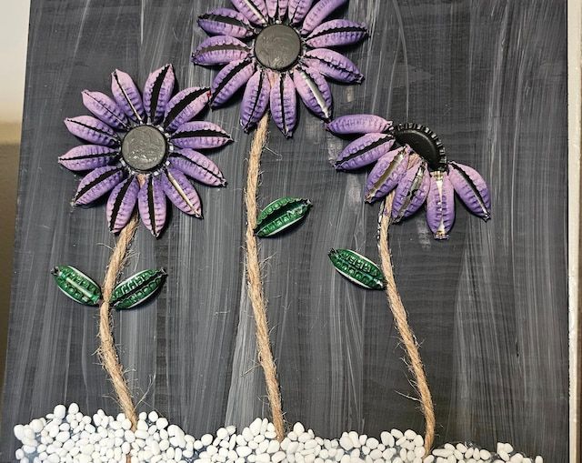 three purple flowers are on top of white rocks in front of a chalkboard background