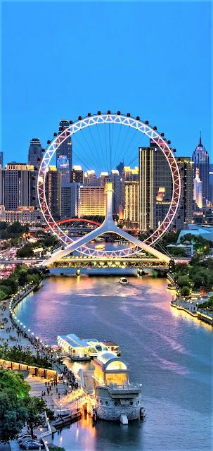 an aerial view of a city with a ferris wheel in the foreground and other tall buildings