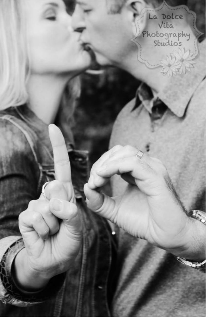 a man and woman kissing each other with the fingers in the shape of a peace sign