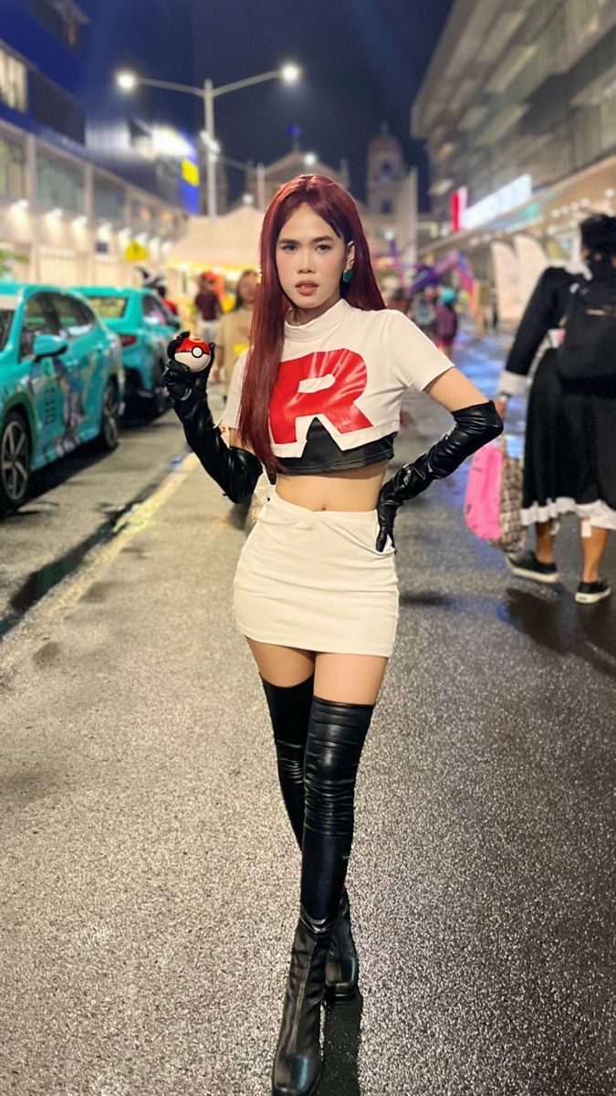 a woman with long red hair and black boots is standing in the street