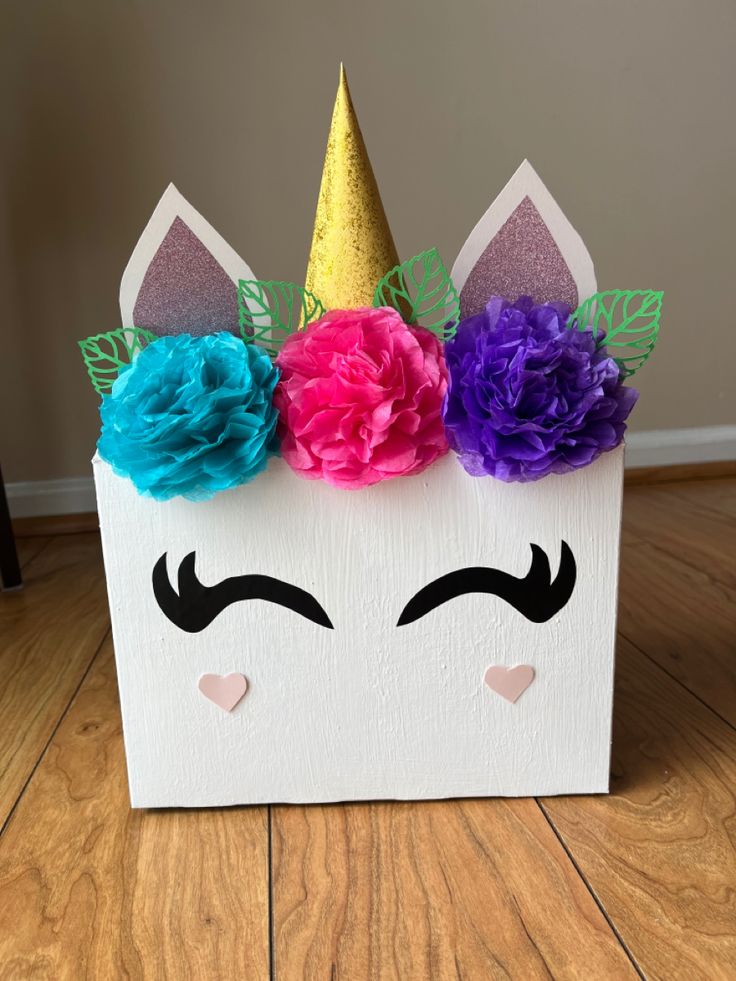 a paper box with a unicorn's face painted on it and flowers in the middle