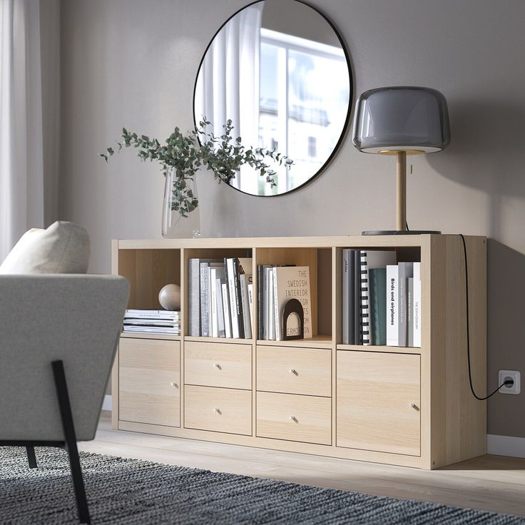 a living room with a book shelf, mirror and lamp on the wall above it