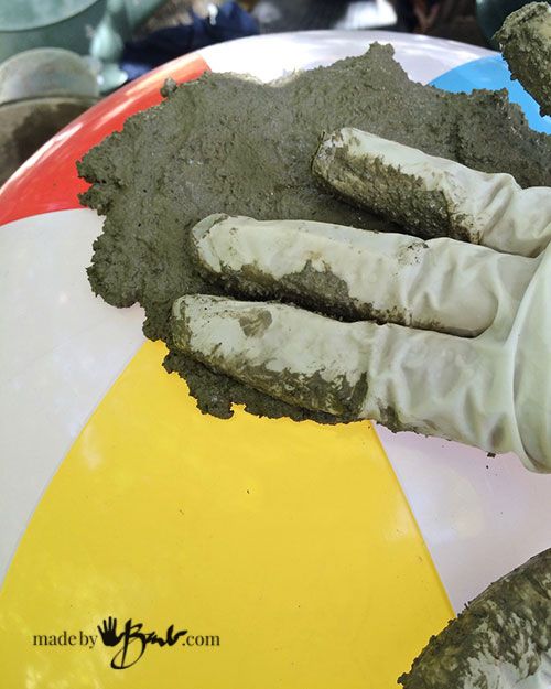 a person's hand with white gloves on top of a beach ball covered in mud