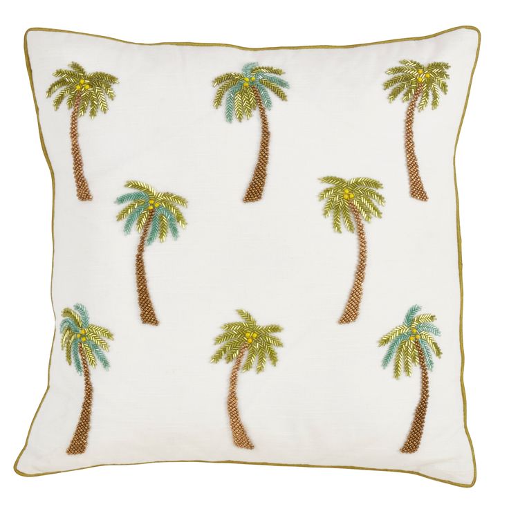 a white pillow with palm trees on the front and back, in gold trimmings