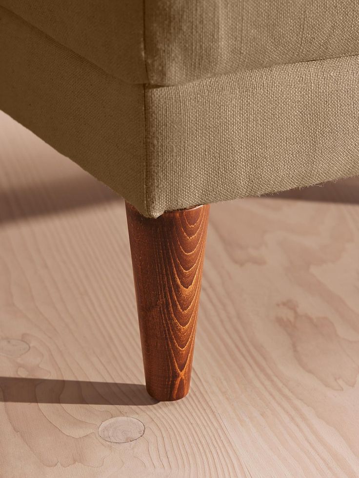 an upholstered bench with wooden legs and wood grained finish on the floor