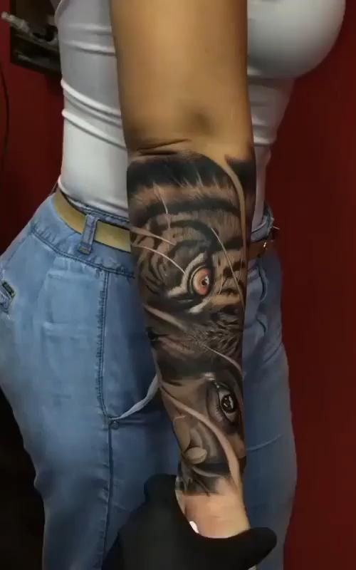 a woman's arm with a tiger tattoo on it and an eyeball in the middle