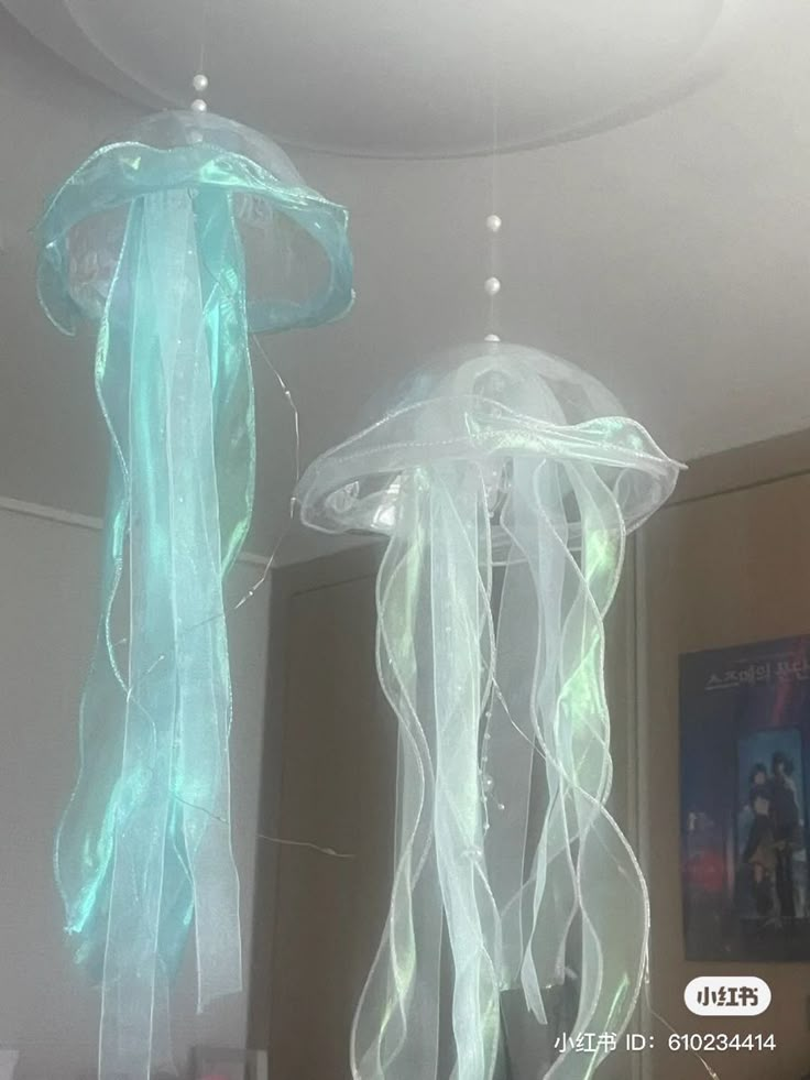 there are two jellyfishs hanging from the ceiling in this room, one is blue and the other is white